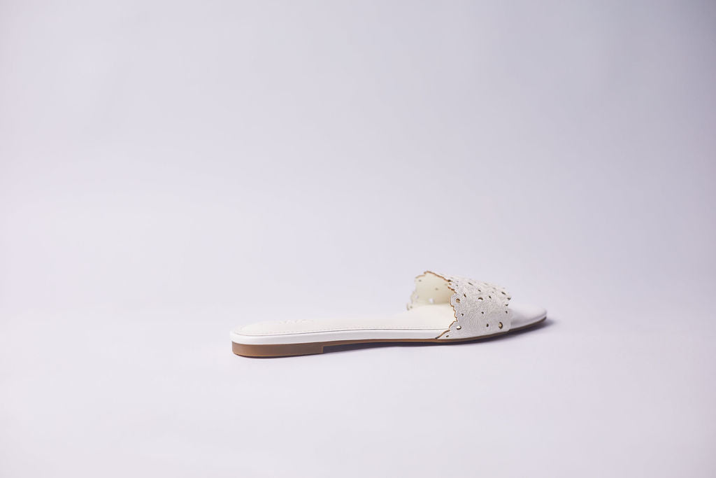 A single white leather slide sandal with decorative metallic studs on the strap, shown from a side profile against a clean white studio background.