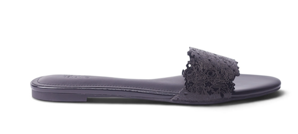 A single dark purple flat slide sandal with a textured floral lace-up strap, shown in profile against a white background.