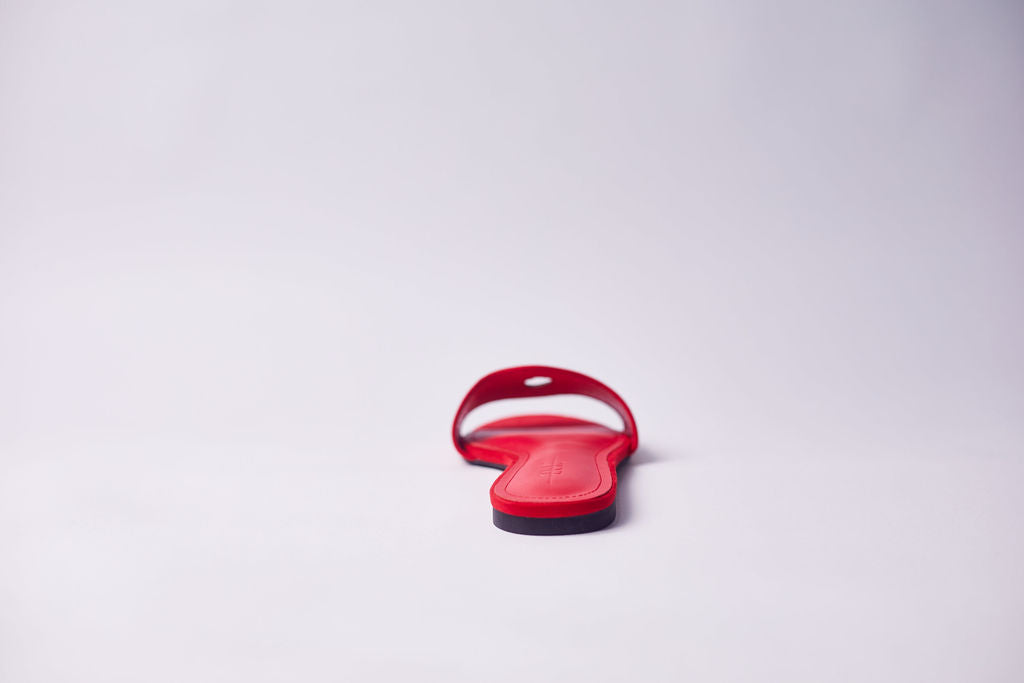 A single red slide sandal shown from the back on a clean, light gray studio background.